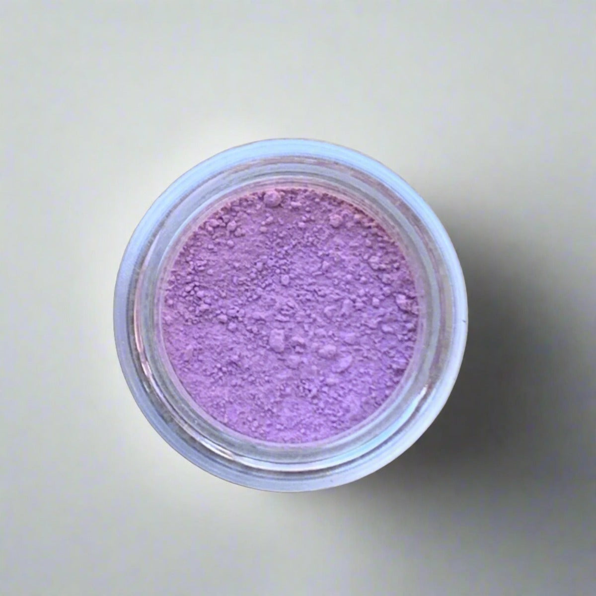 Cosmetic jar of soft pink eyeshadow loose powder, displaying its color and texture