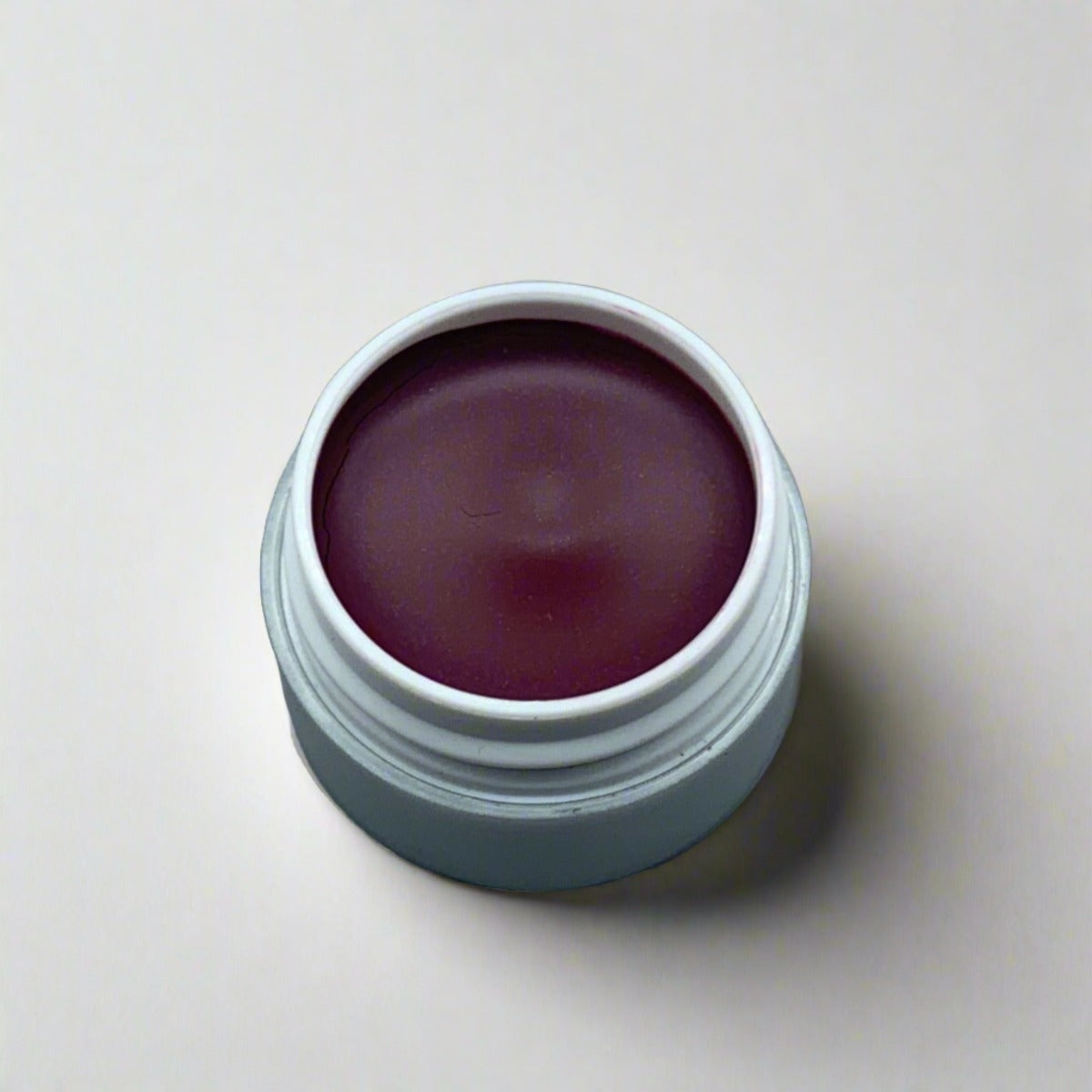 Cosmetic jar of black raspberry lip crème displaying its color and texture