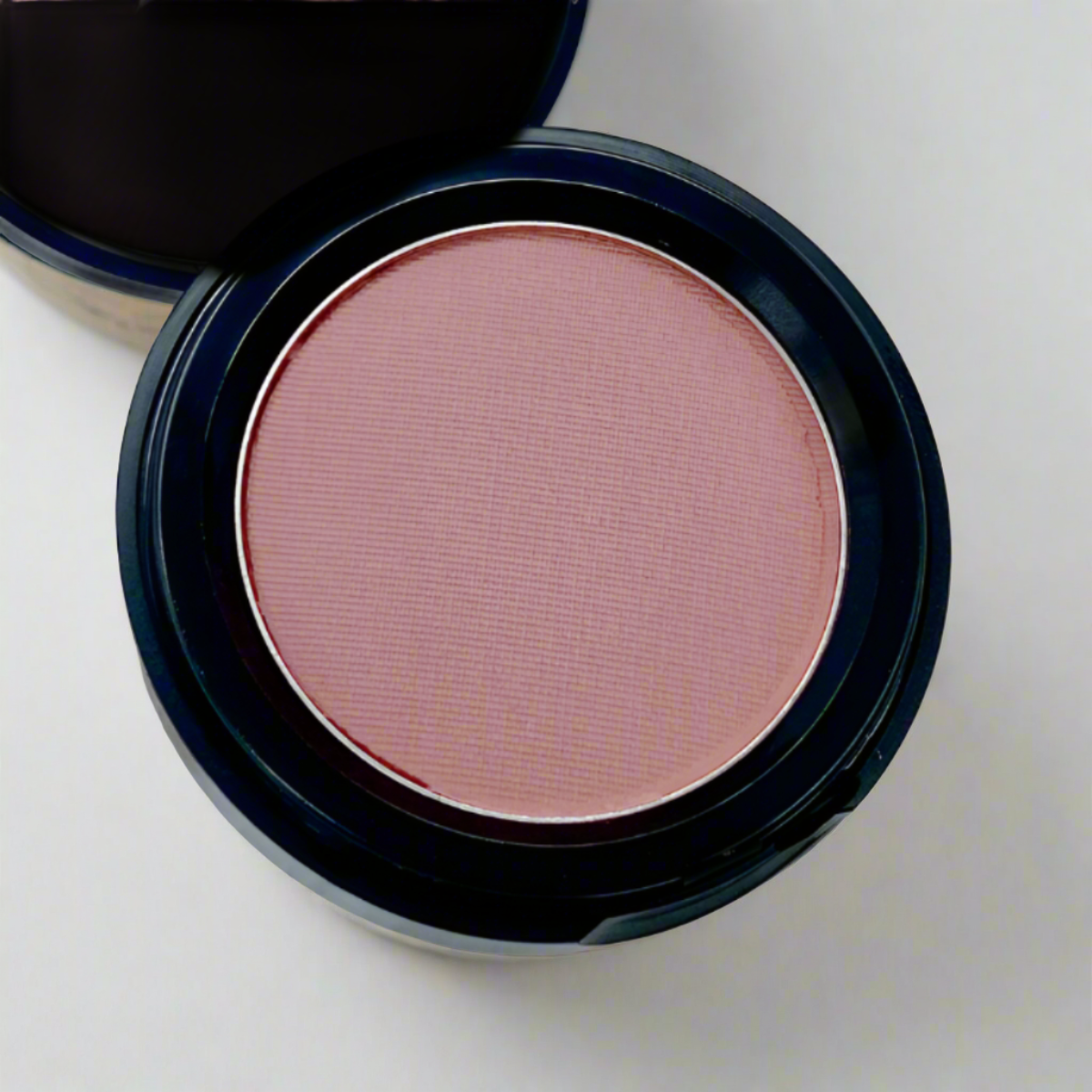  Cosmetic container of light mauve pink matte pressed blush displaying its color and texture