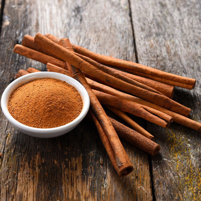 Cinnamon sticks with bowl of cinnamon powder representing product fragrance