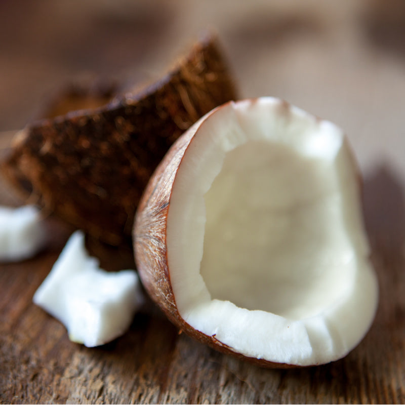 Closeup of a coconut split in half exposing coconut meat on wood background