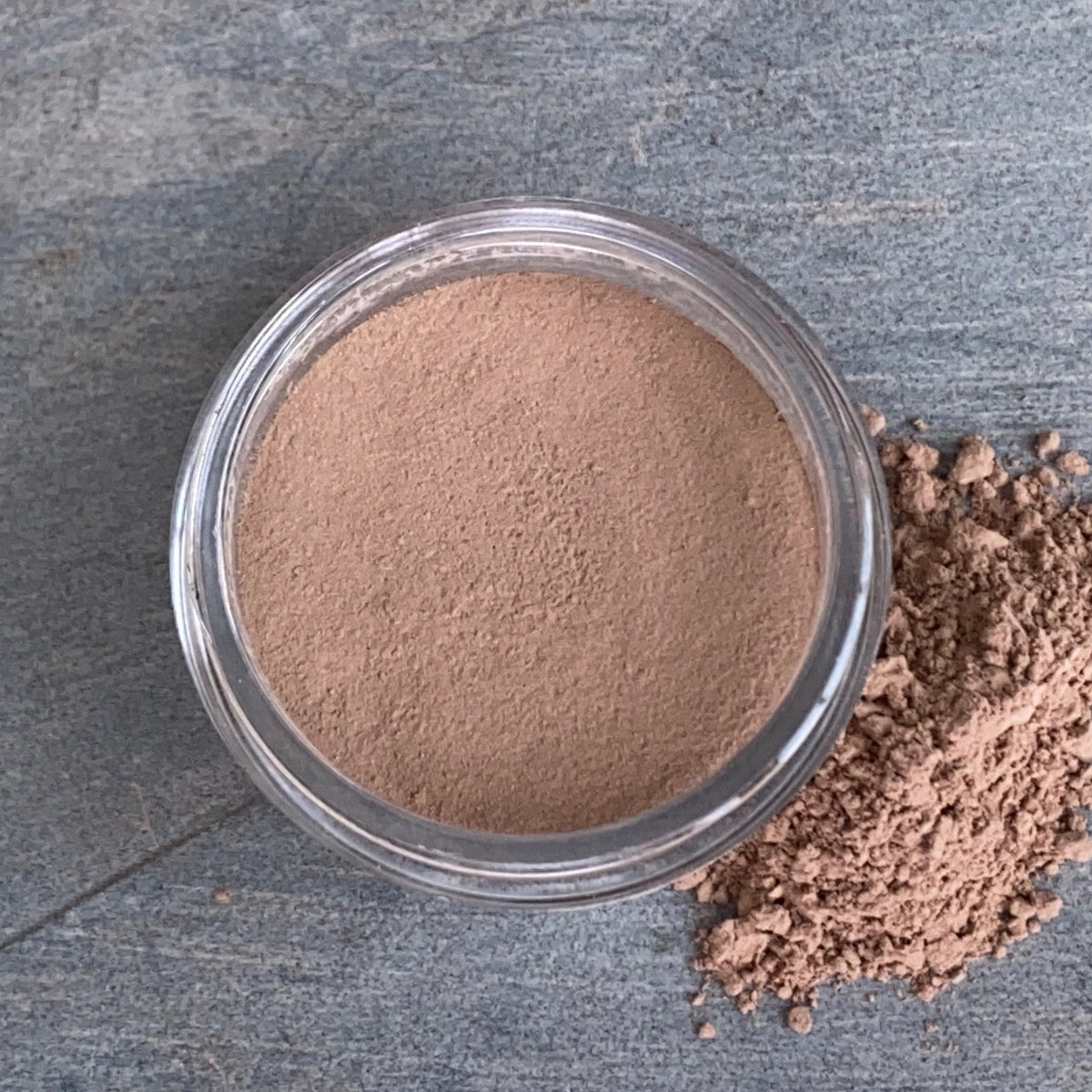 Cosmetic jar of cocoa-hued blush loose powder bronzer displaying its color and texture