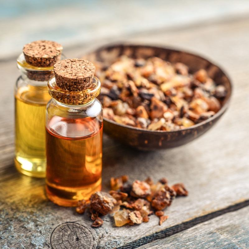 Bottle of myrrh oil with bowl of dried myrrh in background