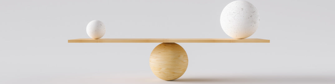 A wooden balance balancing wooden balls on a gray background