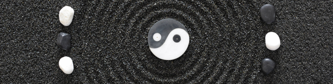 yin yang rocks in black sand representing mindful beauty for health