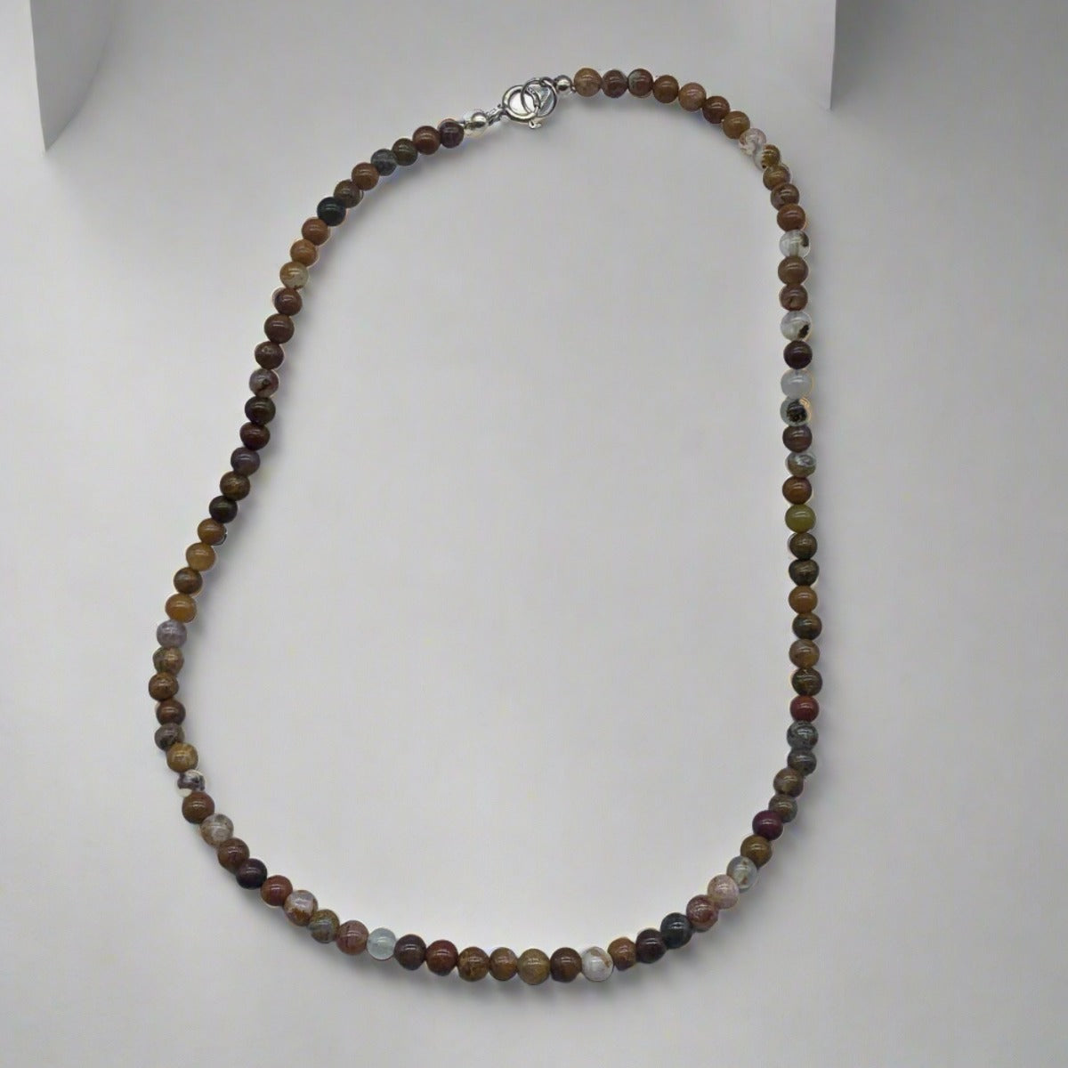 Agua Nueva Agate Necklace: A necklace featuring brown and beige hues with banded pattern stones and a sterling silver jump ring clasp