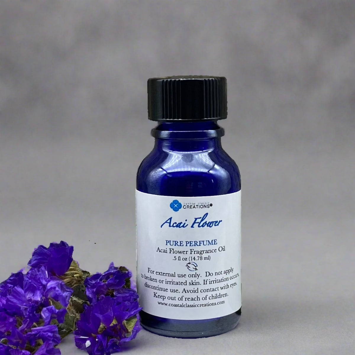Half-ounce blue bottle of Acai Flower Perfume with a black cap and labeled with the product name and ingredients