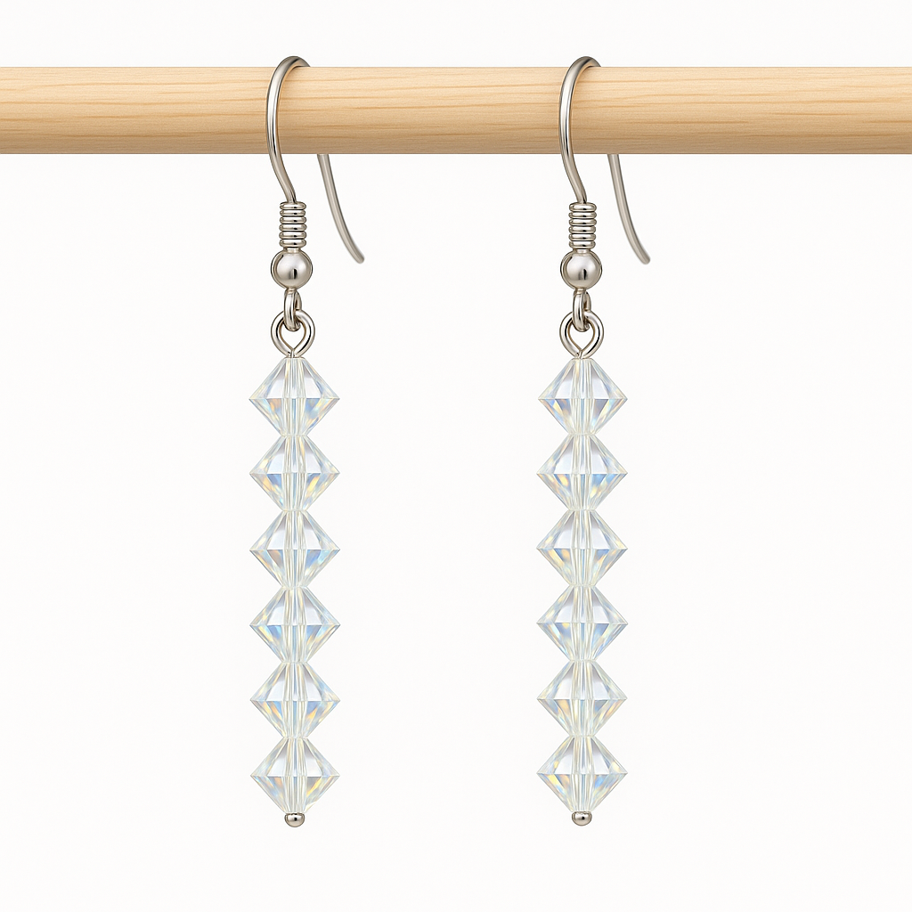 Crystal drop earrings on a wooden rod against a white background