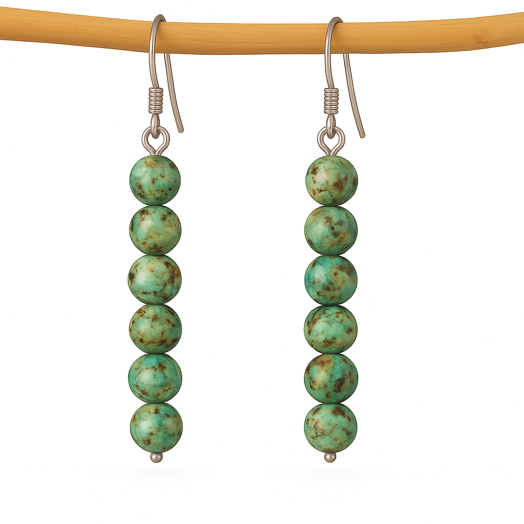 Turquoise bead earrings on a wooden stick against a white background