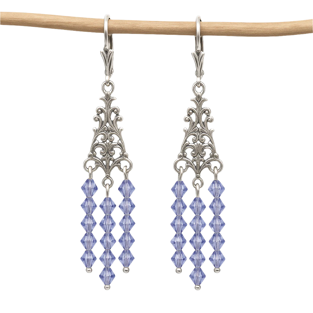 Chandelier earrings with silver filigree and tanzanite blue crystal beads, shown hanging on a wooden rod against white background