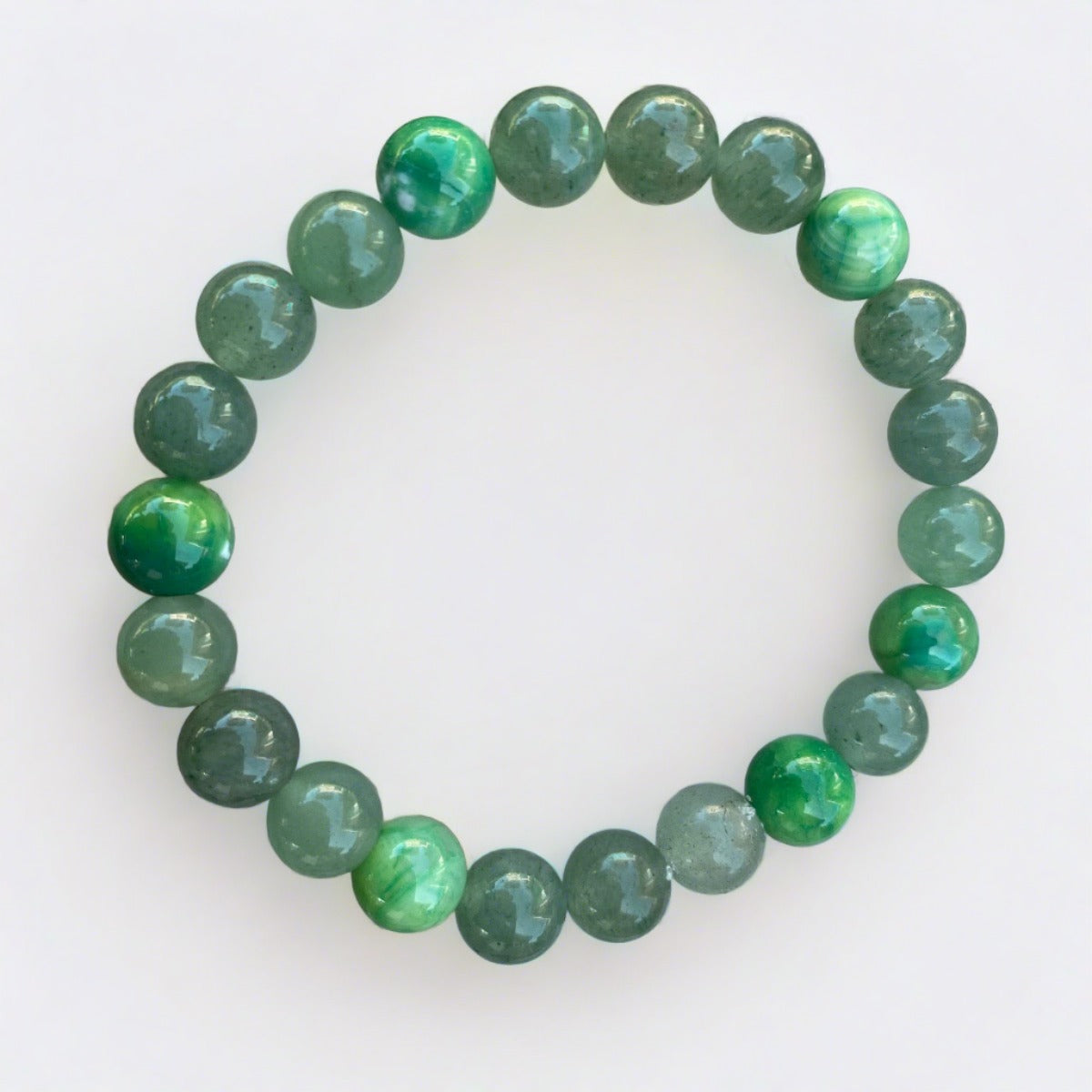 Green agate and aventurine stretch cord bracelet displayed on a natural rock background.
