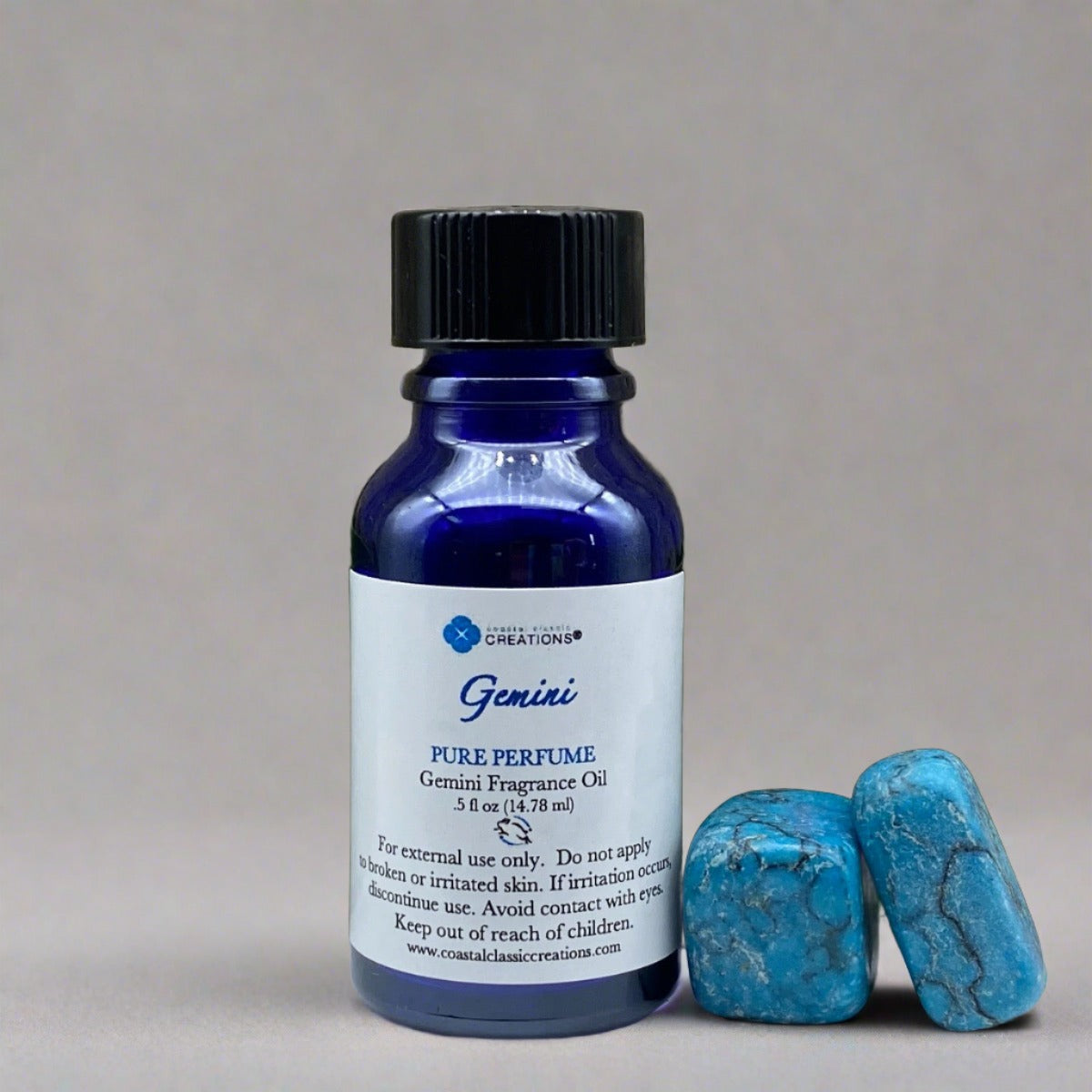 Bottle of Gemini perfume with turquoise rocks on leaf and rock background