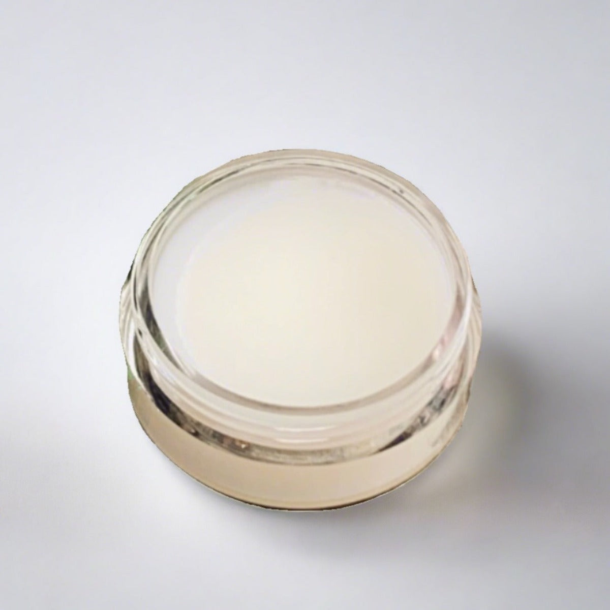 Cosmetic jar of argan eye balm showcasing its pale yellow color and creamy texture
