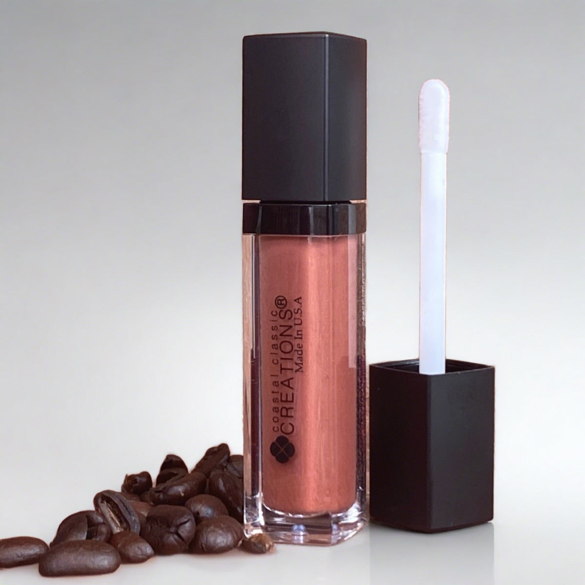 2-in-1 lipgloss and lip plumper Pink Icing Hemp Lip Gloss on rock background with coffee beans