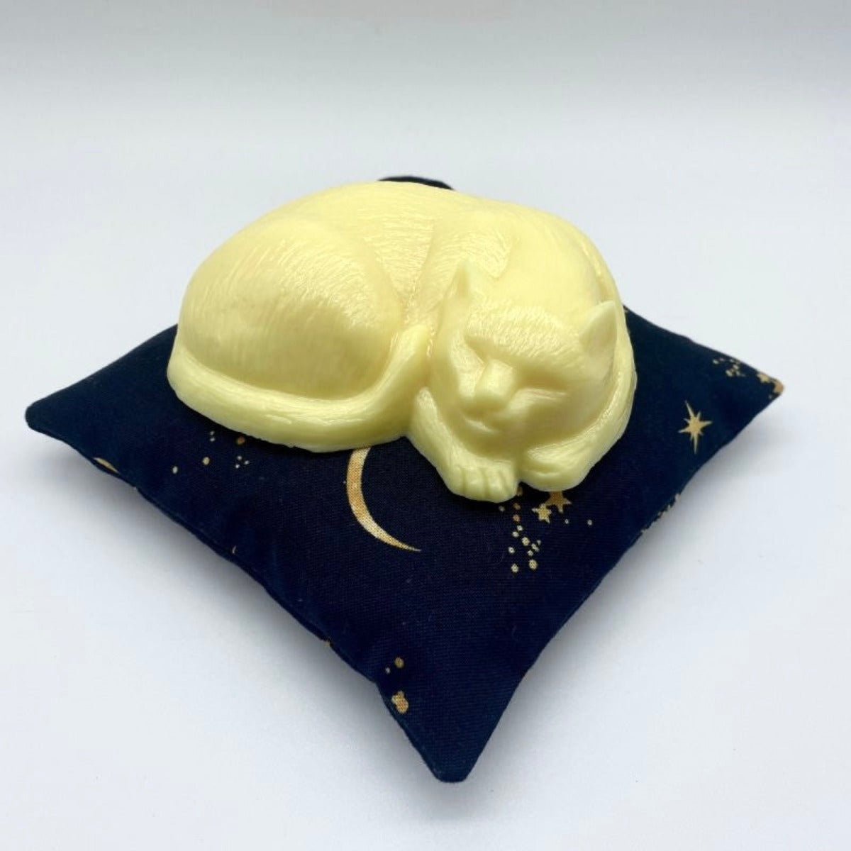 Mindfully sleeping yellow cat-shaped soap, representing the essence of mindful beauty, resting on a celestial navy blue pillow with stars