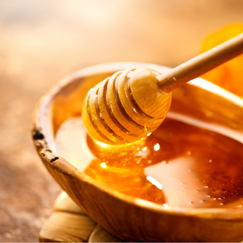 Bowl of raw honey with natural wood honey spoon