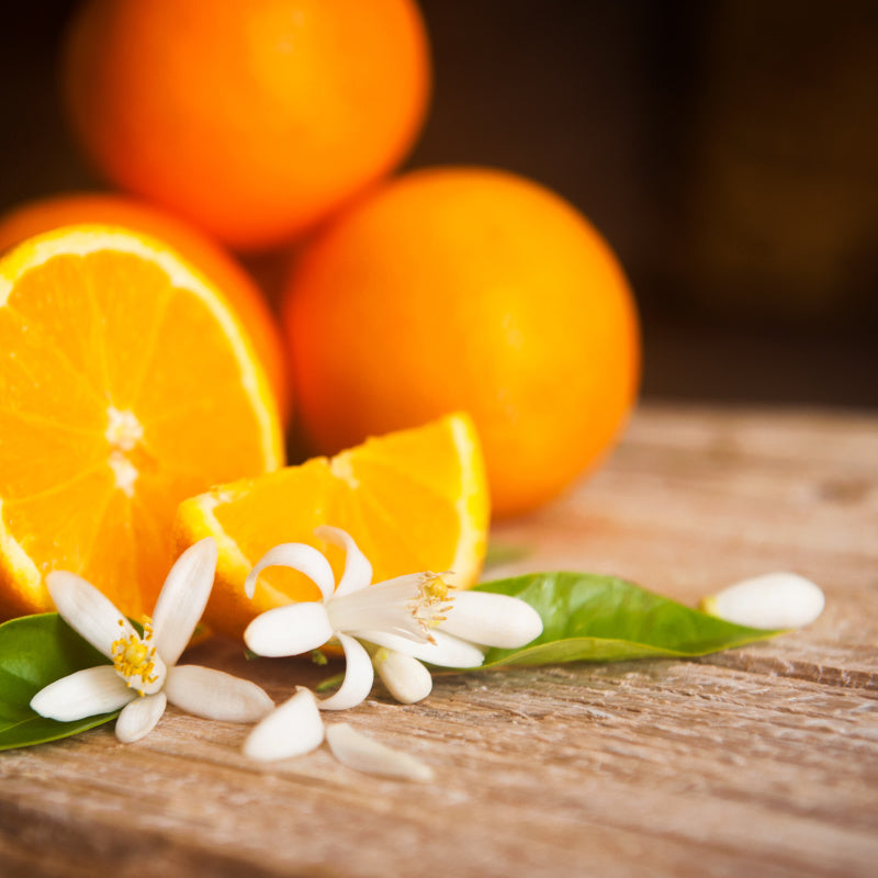 Oranges and orange blooms as pure ingredient Bay Rum perfume on wooden table