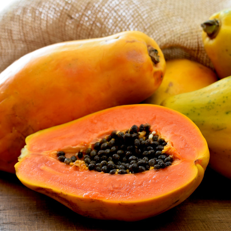 Closeup of papaya cut open with seeds on wooden table